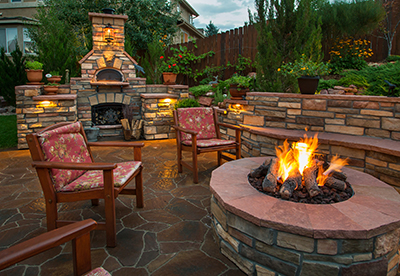 A fire pit burns on a patio during sunset.