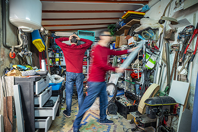 Two men work on decluttering a garage.
