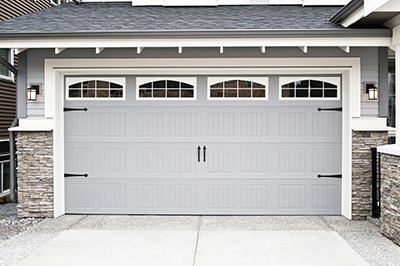 A garage door with accents and book ended by decorative lights.