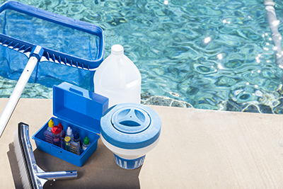 Pool water test kit sits next to a swimming pool.