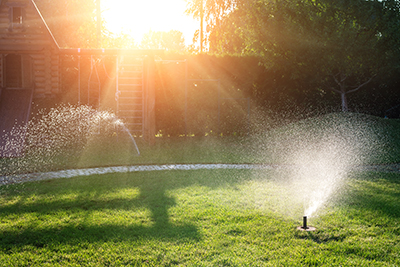 A lawn is watered by a sprinkler system in the morning.