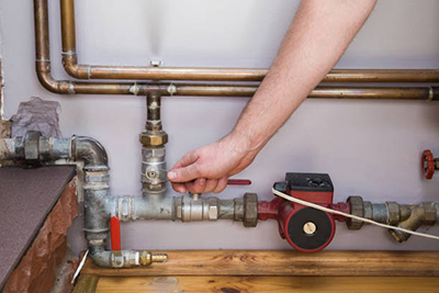 Worker turns off the water supply valve to the sprinkler system.