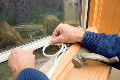 Person applying weatherstrip to window frame