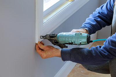 A framing nailer is used to attach moulding around a window frame.