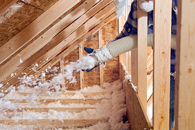 Loose-fill insulation is blown into a crawl space of a garage.