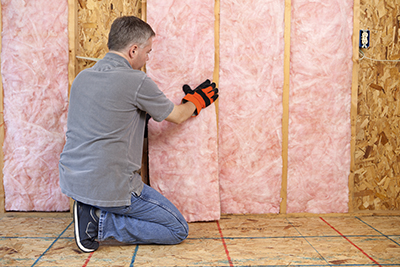 A man installs fiberglass insulation.