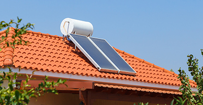 A water heating solar panel sits on the roof of a home.