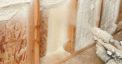 Spray foam insulation is applied between wall studs.