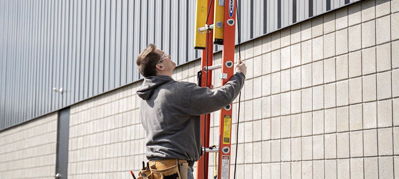 A worker extends a Werner GLIDESAFE ladder.