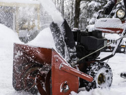 A snow blower is used to clear snow from a driveway.