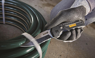 A DEWALT spring-assisted pocket knife cuts through a zip tie.