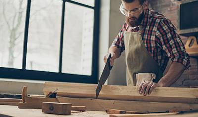 A handsaw is used to cut down a piece of lumber.