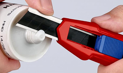 A Knipex snap-off utility knife cuts the tip of a tube caulk.