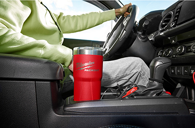 A Milwaukee PACKOUT 20-ounce tumbler sits in a cup holder.