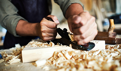 A planer smooths out a piece of wood.