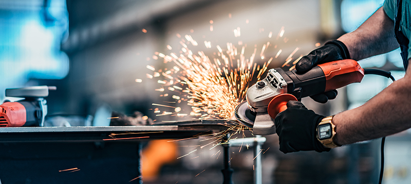 A worker uses an angle grinder safely.