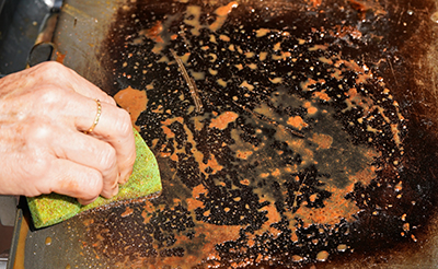 A scrubber is used to clean a flat top grill.