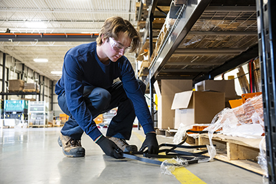 A man cleans trash off the floor to prevent fall hazards.