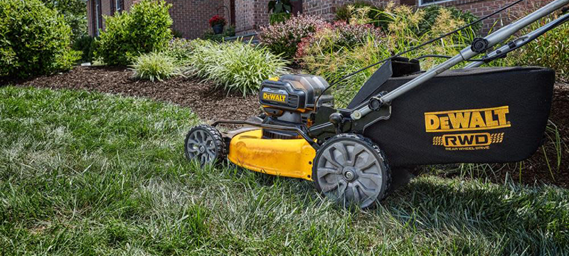 A DEWALT 2x20V MAX XR Cordless Lawn Mower is pushed up hilly terrain.