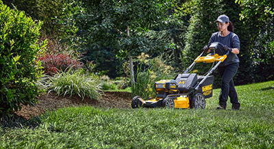 A DEWALT 2x20V MAX XR Cordless Lawn Mower is used to cut tall grass.