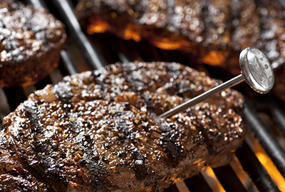 A dial meat thermometer is used to measure the temperature of a steak.