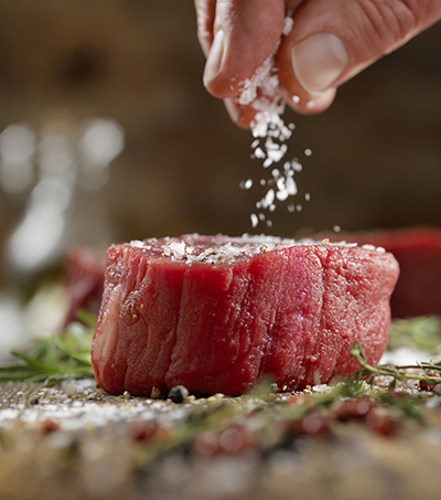 Flaky salt is used to season a filet mignon steak.