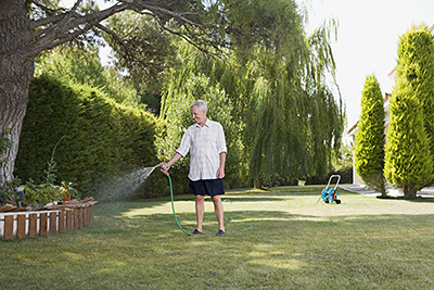 A man watering his lawn with a hose.