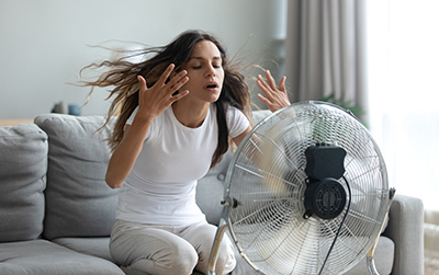 A woman cooling off in front of a fan.
