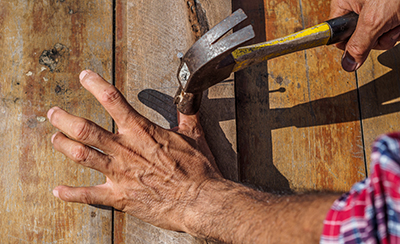 A man accidentally hits his thumb with a hammer.