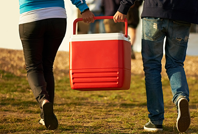 A couple carries a cooler.
