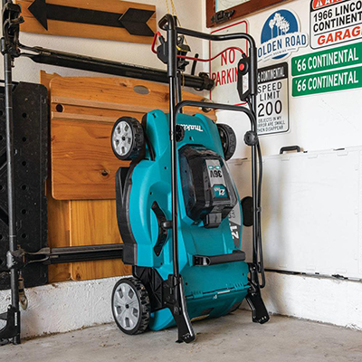 A Makita 36V LXT Lawn Mower folded in an upright position in a garage.