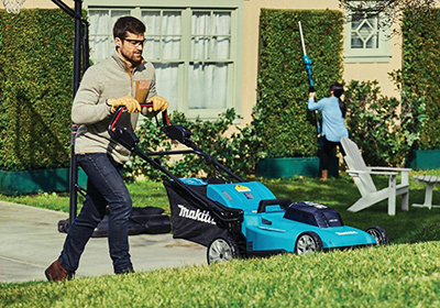 A Makita 36V LXT Lawn Mower is pushed up a hill.