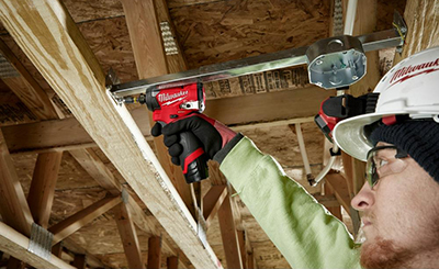 A Milwaukee M12 FUEL Impact Driver is used to secure a junction box to a roof joist.