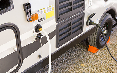 A hose is connected to the water tank of an RV.