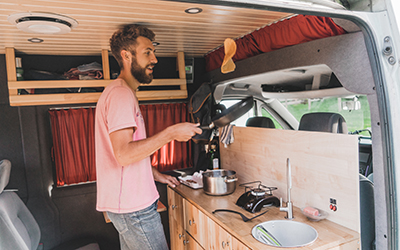 A man cooks pancakes inside the kitchen of his RV.