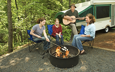 A family roast marshmallows while sitting around a campfire.