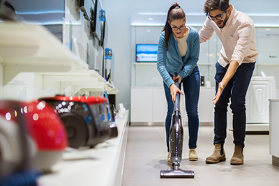 An employee helps a woman shop for a vacuum.