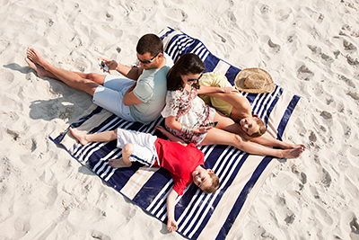 A family lays on a beach towel.