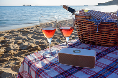 A bluetooth speaker sits on a table on a beach.