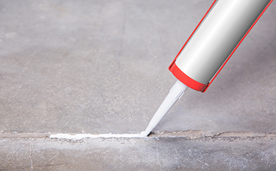 Caulk is applied to a crack in a concrete floor.
