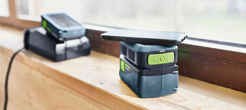 A phone charges wirelessly on the Festool Mobile Phone Charger.