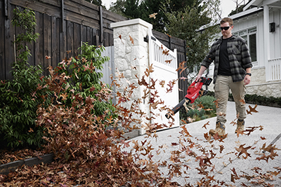 A Milwaukee M18 FUEL Dual-Batter Blower is used to blow leaves of a driveway.