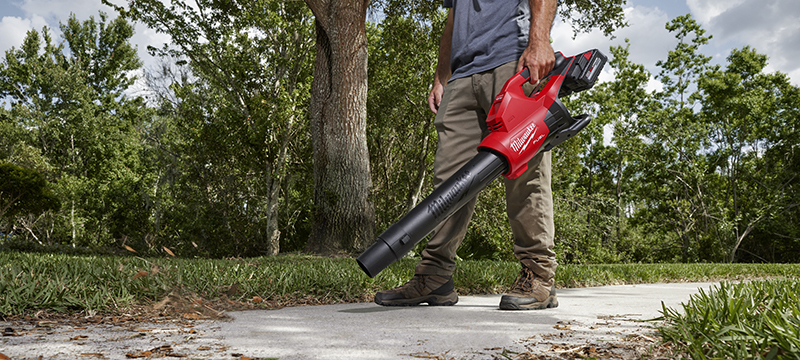 A Milwaukee M18 FUEL Dual-Batter Blower is used to blow debris off a sidewalk.