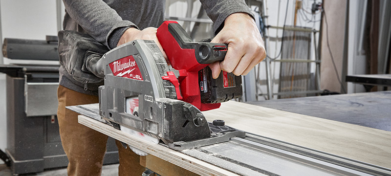 A Milwaukee M18 FUEL Plunge Track Saw makes a straight line cut in a piece of plywood.