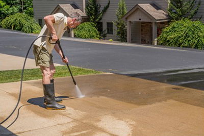 A pressure washer is used to clean the cracks in a cement driveway.