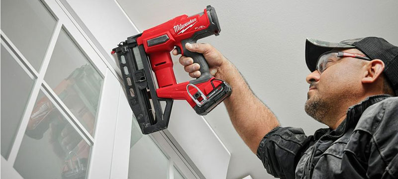 carpenter using the milwaukee 3020-20 finish nailer to apply some trim around a door