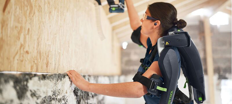 Carpenter using the Festool Exoseleton to hang some plywood on a wall.